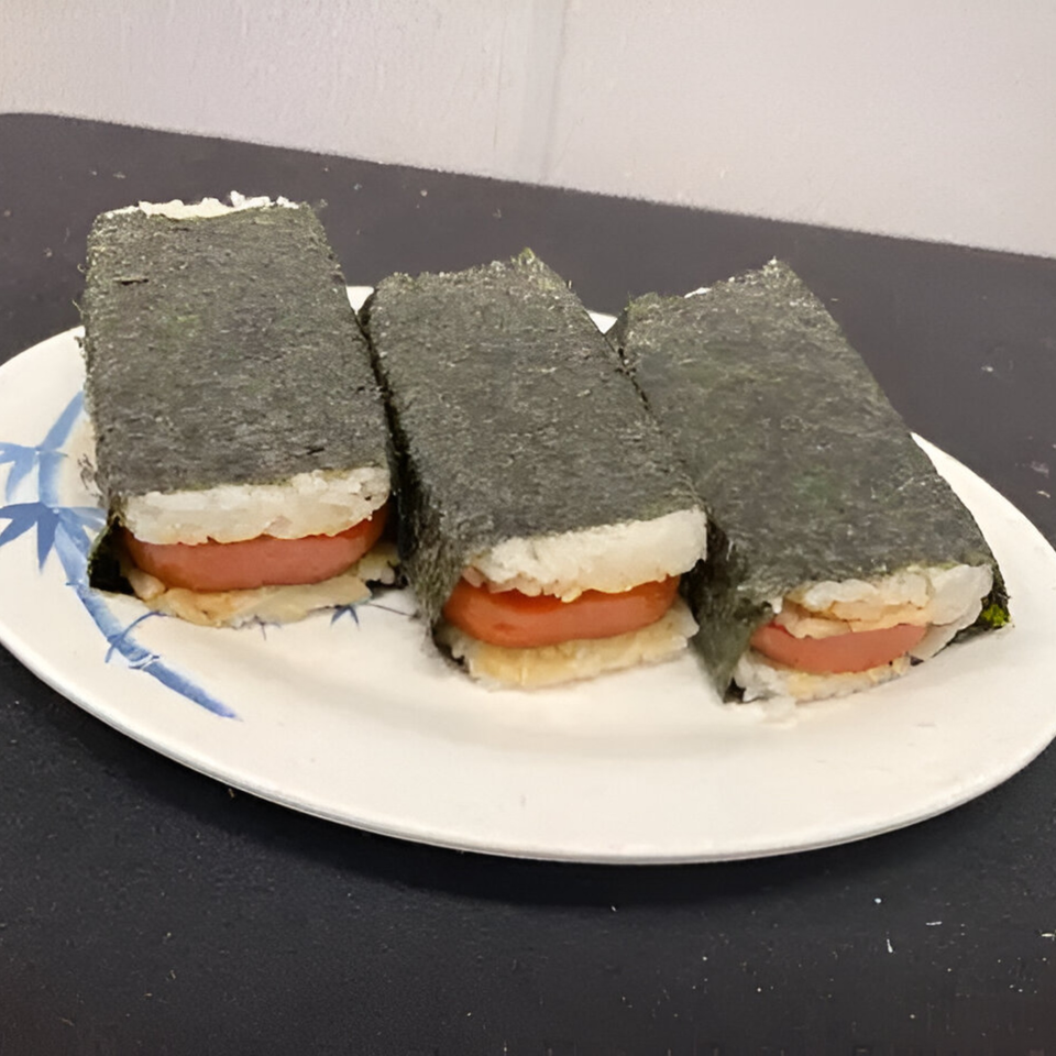 Three Kuya's Islander Cuisine Spam Musubi, with rice and Spam wrapped in nori, on a white plate.
