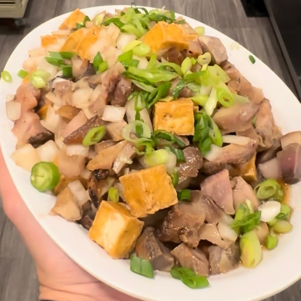 A close-up of Kuya’s Islander Cuisine's sisig, featuring diced meat, tofu, onions, and green onions.