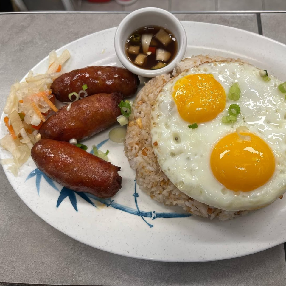 Filipino longganisa sausages, garlic fried rice, two fried eggs, and pickled vegetables on a plate.