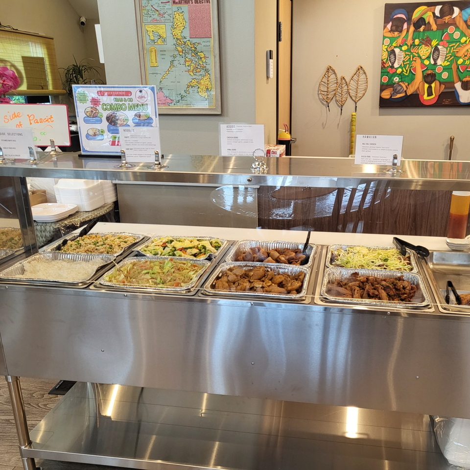 A Kuya’s Islander Cuisine buffet line with Filipino dishes like adobo, pancit, and rice.